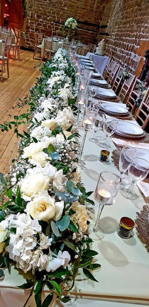 Top table at the wedding with green and white flowers