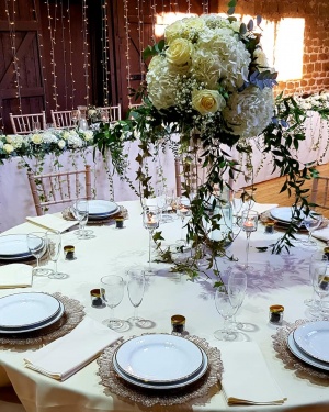 Table set up in a wedding barn with charger plates and floral display